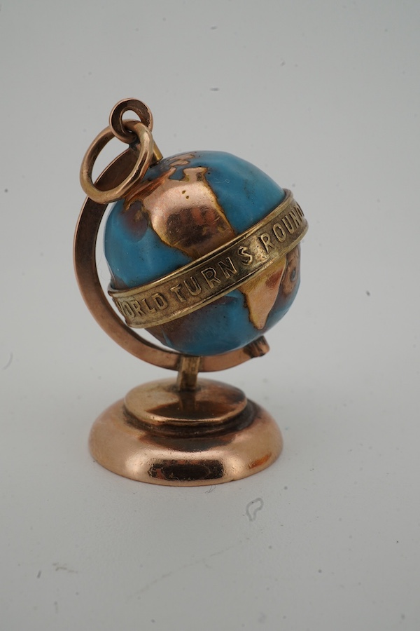 A yellow metal and enamel globe charm, reading 'The whole world turns round the love', height 3.2cm; and a gold and amber pendant, length 4.5cm, Russian assay marks for 14ct gold